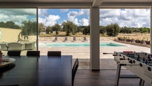 Ein Zimmer mit Pool, Sitzgelegenheiten im Freien und einem Kicker.