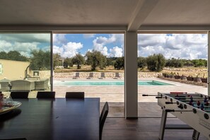 Ein Zimmer mit Pool, Sitzgelegenheiten im Freien und einem Kicker.