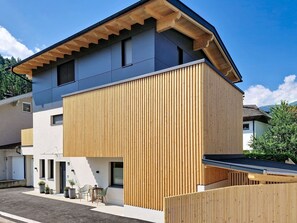 Una casa moderna de dos pisos con fachada de madera y techo inclinado.