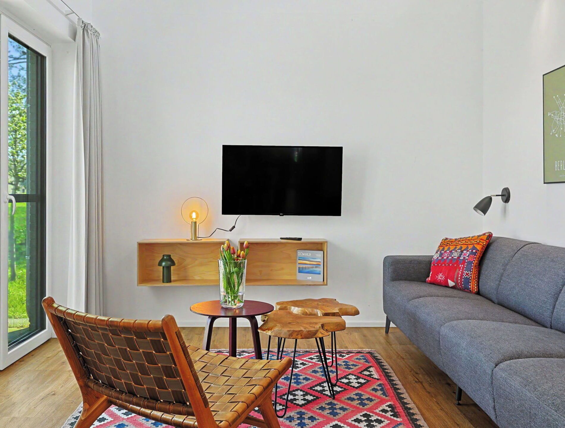 Una sala moderna con un sofá, un televisor, una mesita, una silla y una alfombra.