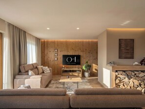 A modern living room with a sofa, a coffee table, a TV, and a fireplace.