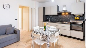 Una cucina moderna con un tavolo da pranzo per due, un divano e una sveglia appesa al muro.