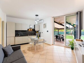 Eine moderne Küche mit Essbereich, einer Couch und Blick auf den Garten.