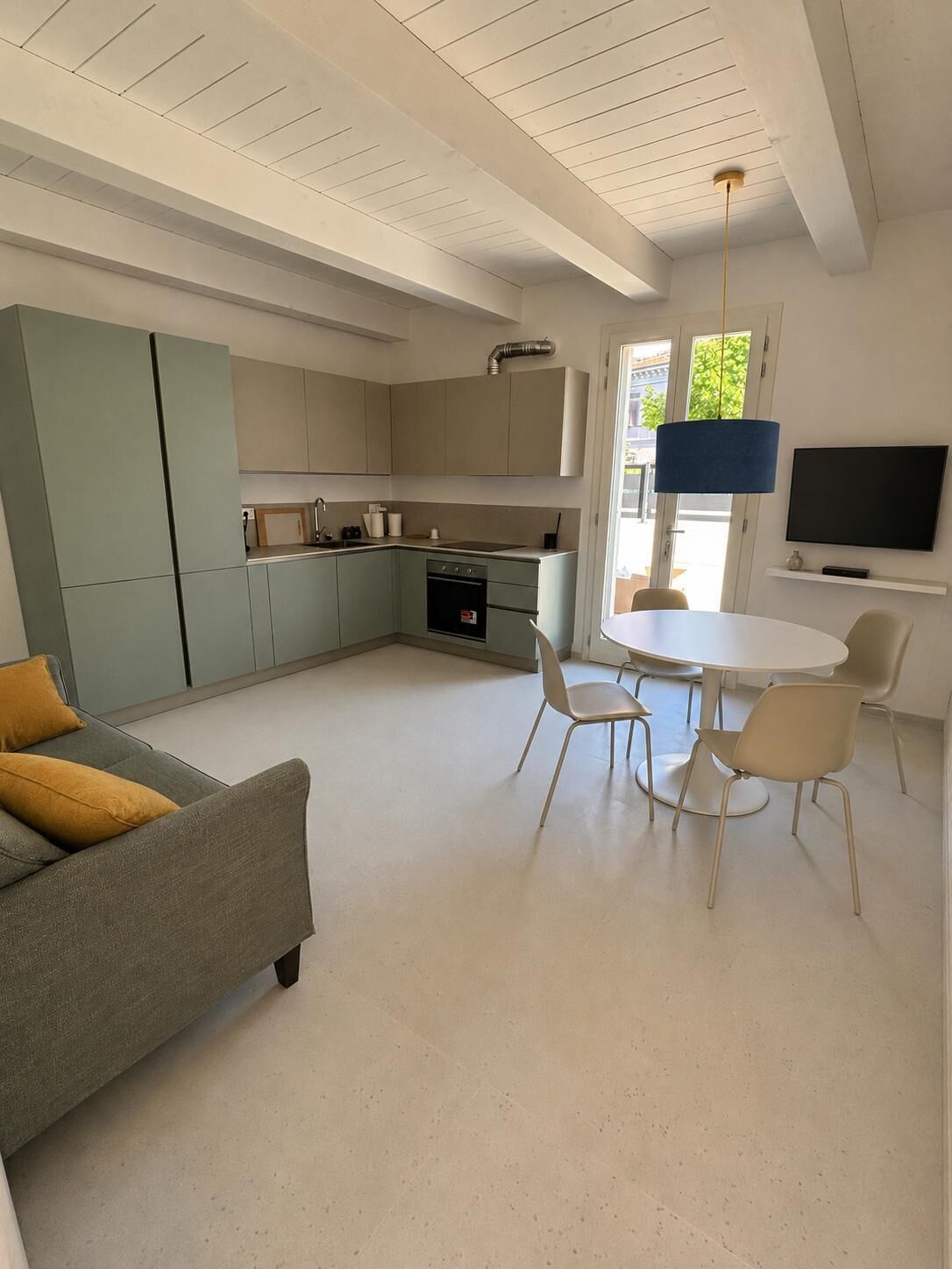 Una cucina moderna con zona pranzo, divano e televisione.