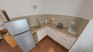 Una cucina compatta con frigorifero, lavandino, piano cottura e pensili.