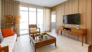 A modern living room with a sofa, coffee table, TV, and a large window. - Gustavo Funchal (Florianópolis)