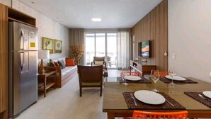 A modern living room with a dining area, a built-in kitchen, and a large window. - Gustavo Funchal (Florianópolis)