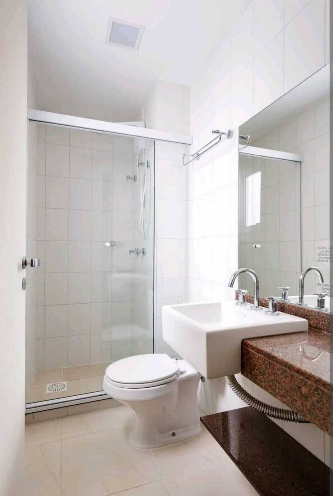 A modern bathroom with a glass shower enclosure, a white toilet, a sink with a mirror, and a granite countertop.