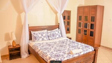 Un dormitorio con cama con dosel, armario de madera y mesita de noche con lámpara.