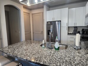 A kitchen with granite countertops, stainless steel appliances, and white cabinetry. - De Premium Place Buckhead- City Center (Atlanta)