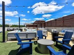 An outdoor patio with blue chairs, a round table, and string lights. - De Premium Place Buckhead- City Center (Atlanta)