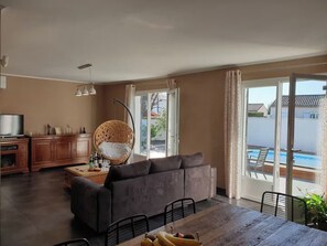 Ein Wohnzimmer mit einer Couch, einem Esstisch und einem Korbstuhl.