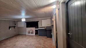A room with a tiled floor, a brick wall, a white door, and a small counter with a vase of flowers. - H&L Self-catering Accommodation (Bonnievale)