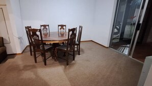 A dining area with a table and chairs, a sofa, and a sliding glass door leading to a balcony. - H&L Self-catering Accommodation (Bonnievale)