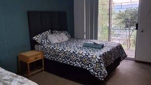 A bedroom with a bed, a nightstand, a ceiling fan, and a window. - H&L Self-catering Accommodation (Bonnievale)