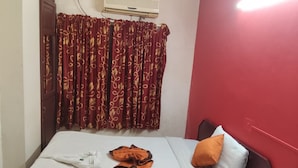 Una habitación con una cama, una ventana con cortinas estampadas y un aire acondicionado montado en la pared.
