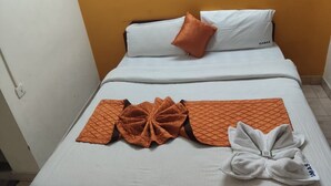 Una habitación de hotel con una cama, almohada, manta y toalla.