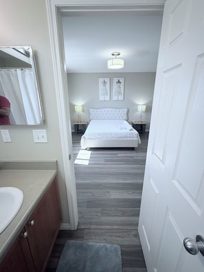 A bedroom with a bed, bedside lamps, a mirror, and a door. - Edmonton, Brinell Park, Comfy Guest Retreat, 3BRs 4 Beds + Sofa bed and 2 car GA (Edmonton)