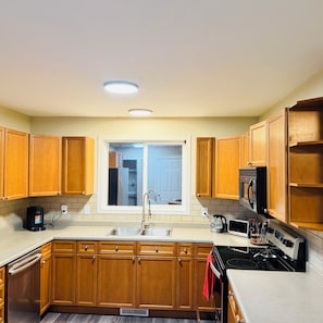 A kitchen with wooden cabinets, a stainless steel sink, a microwave, and a stove. - Edmonton, Brinell Park, Comfy Guest Retreat, 3BRs 4 Beds + Sofa bed and 2 car GA (Edmonton)