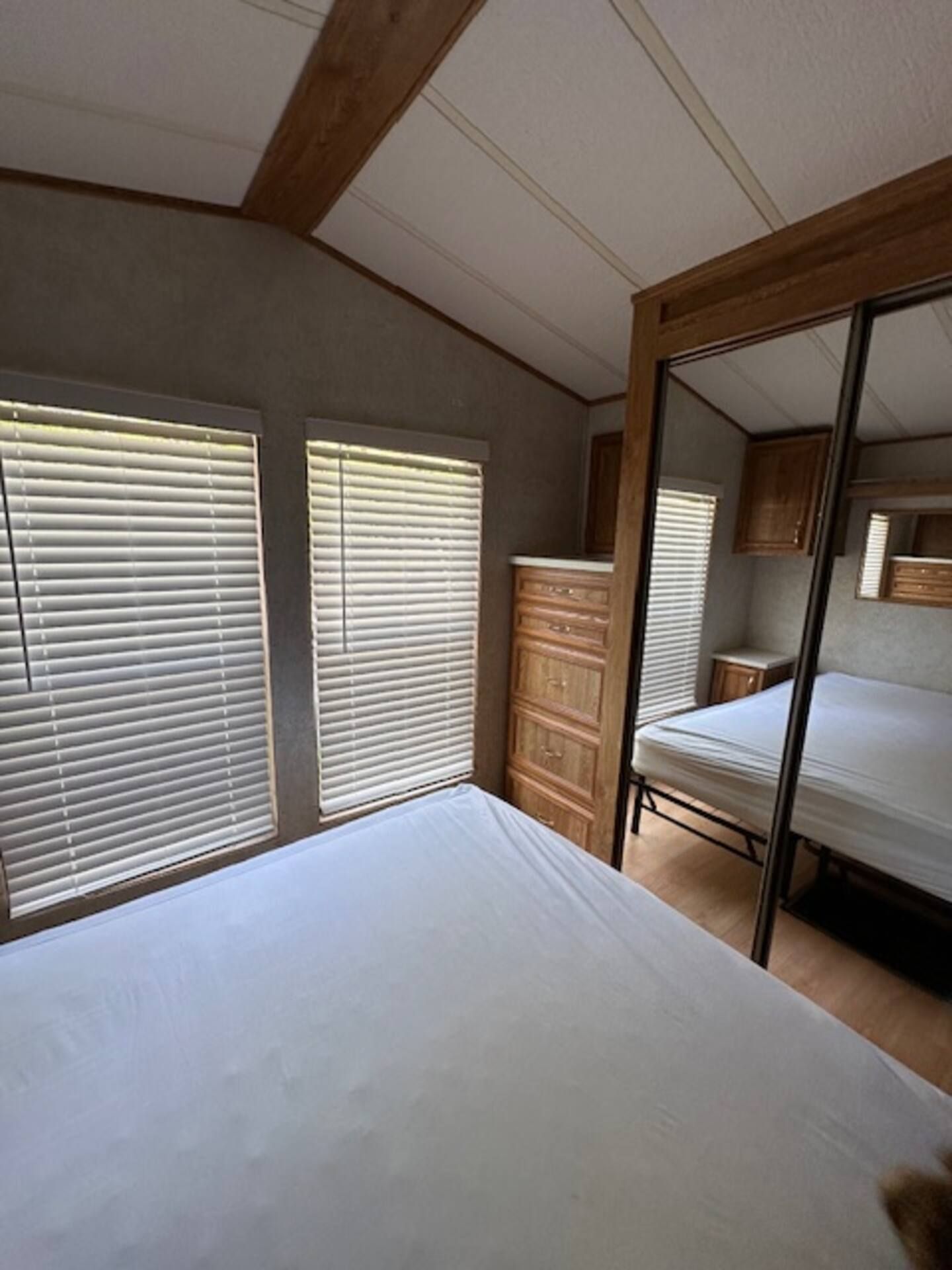 A bedroom with a bed, a dresser, and a mirror.