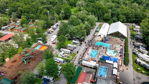 An aerial view of a campground with RVs, swimming pools, and a large tent structure.