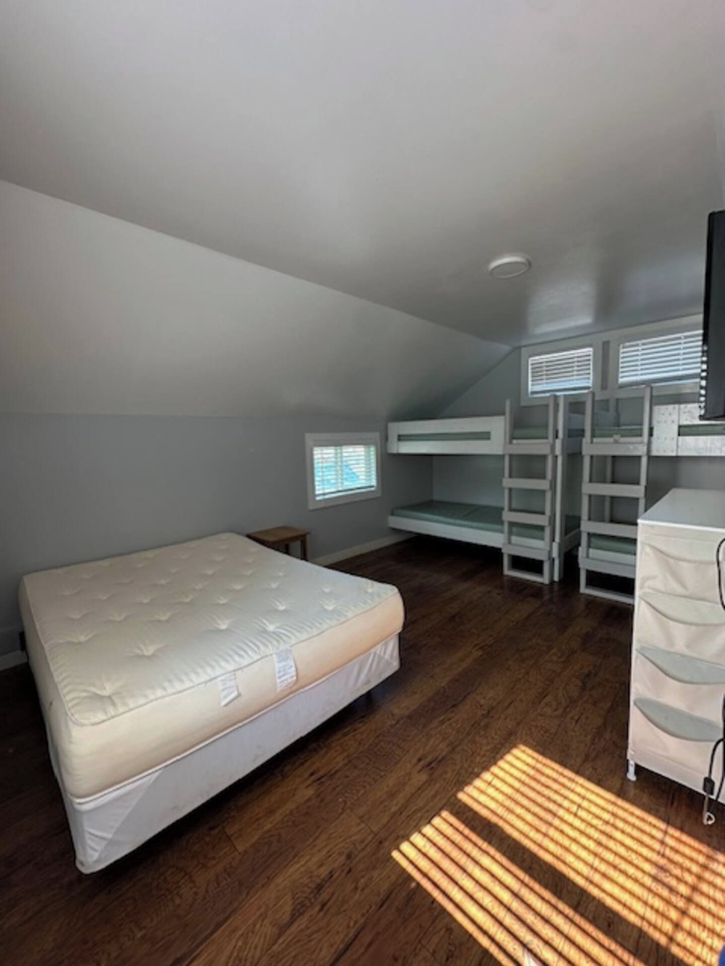 A room with a bunk bed, a desk, and a window.