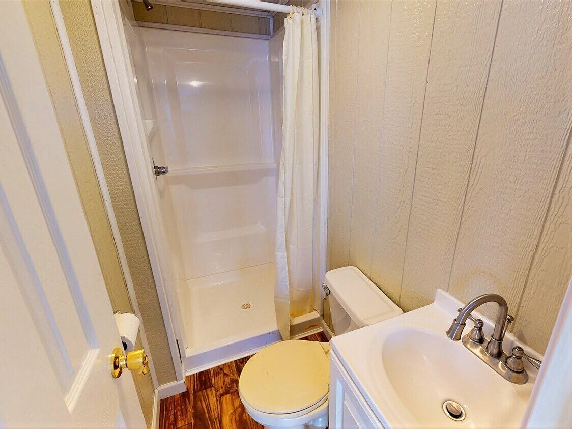 A bathroom with a toilet, sink, and shower.
