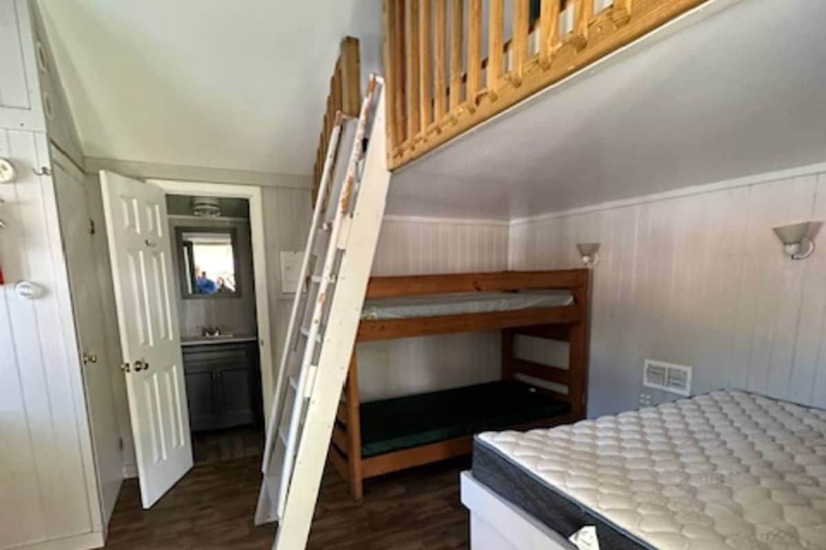 A room with a bunk bed, a wardrobe, and a door leading to another room.