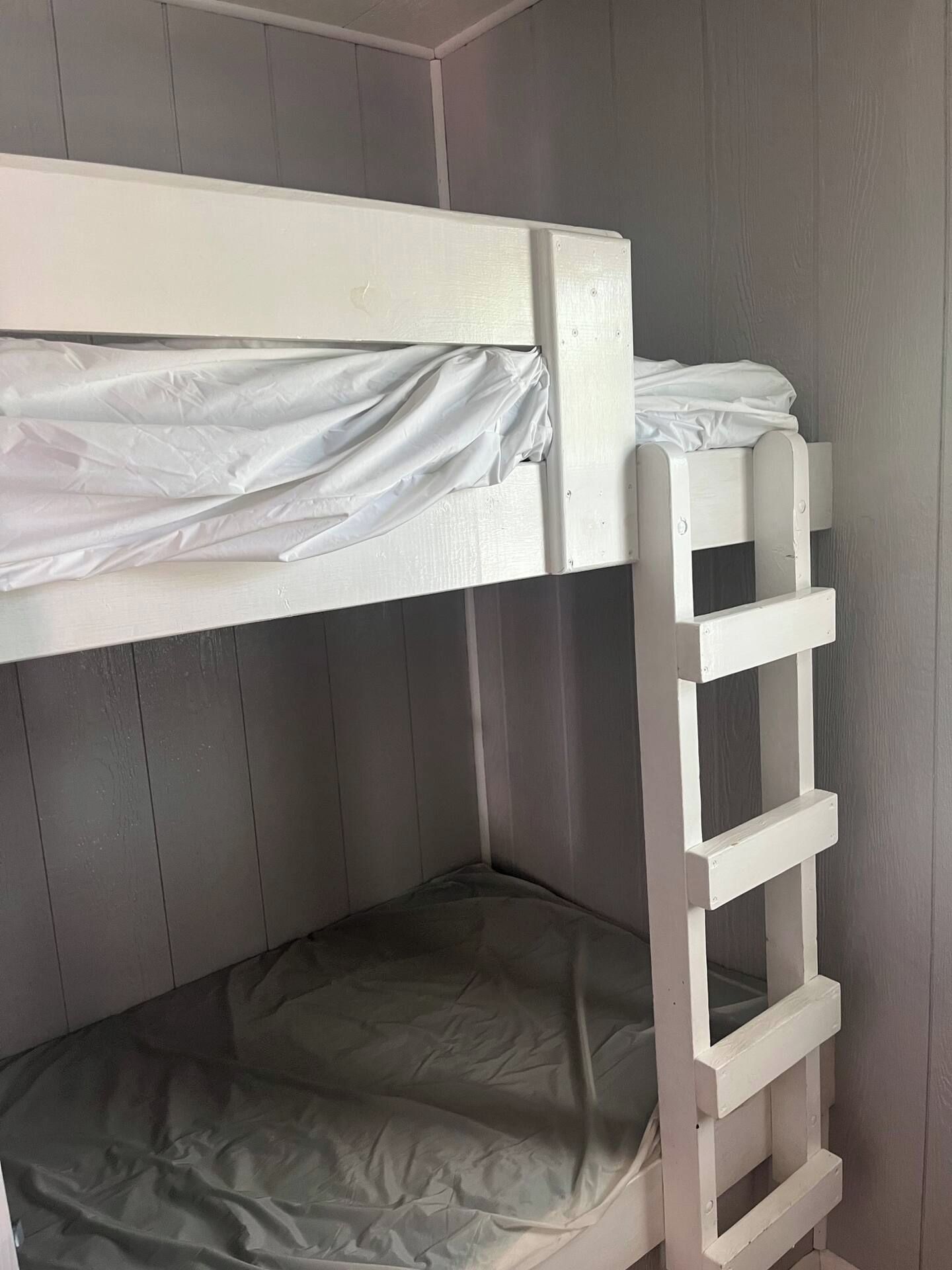 A bunk bed with a ladder, a mattress, and a headboard.