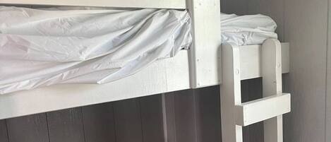 A bunk bed with a ladder, a mattress, and a headboard.