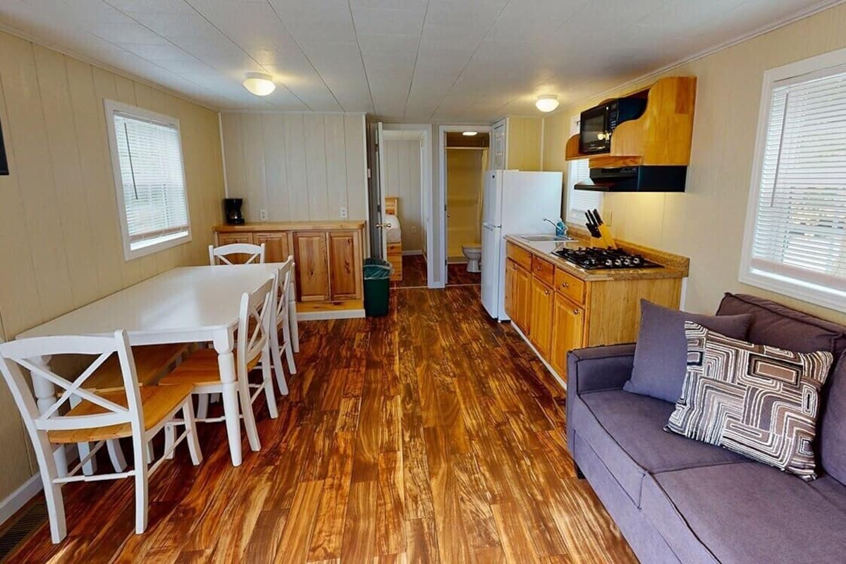 A compact kitchen with a dining table and chairs, a sofa, and a microwave.