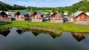 A row of log cabins with a pond in the foreground. - Splash Magic RV Resort (Northumberland)
