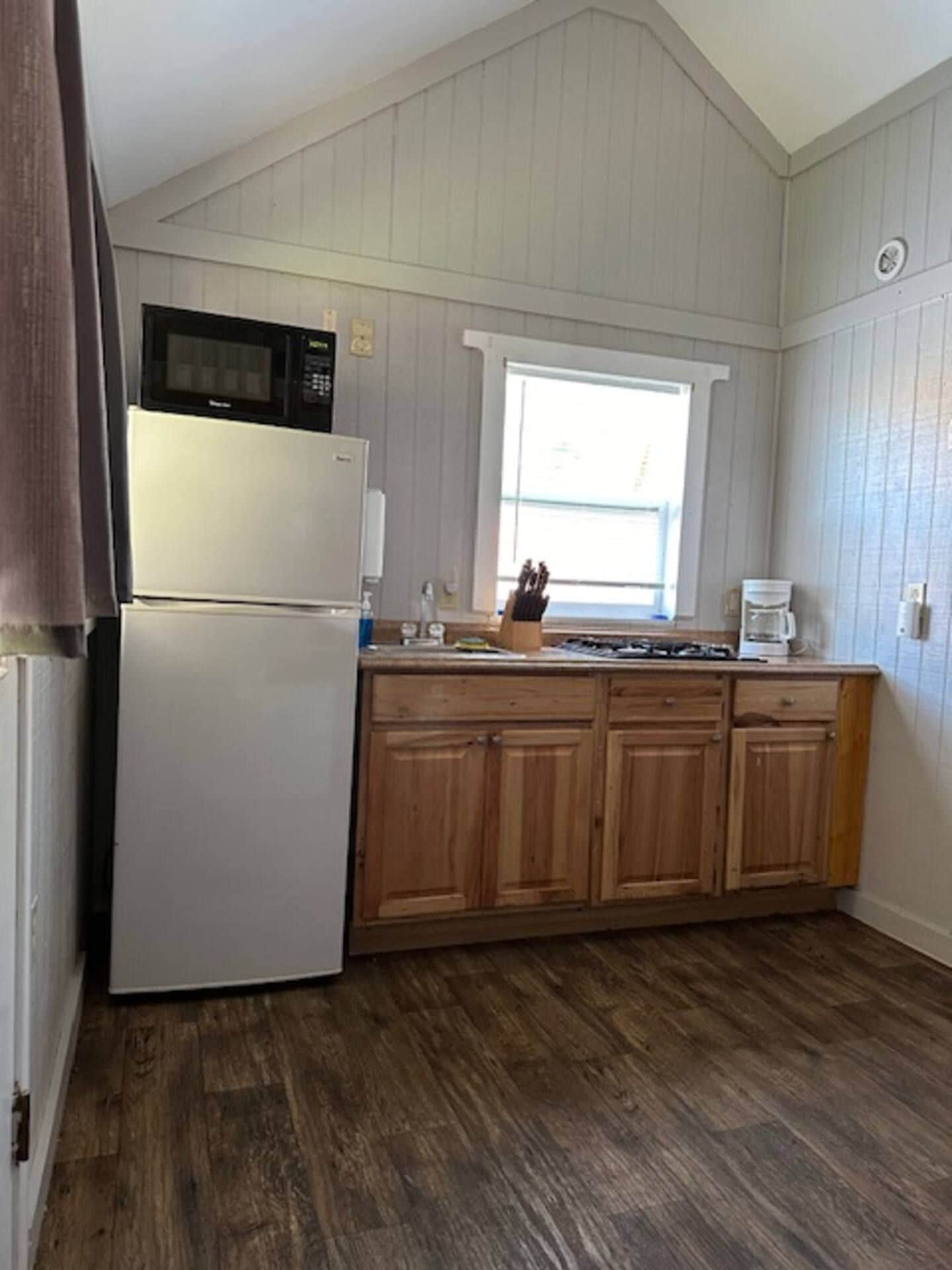 Una cocina con refrigerador, microondas y gabinetes de madera.