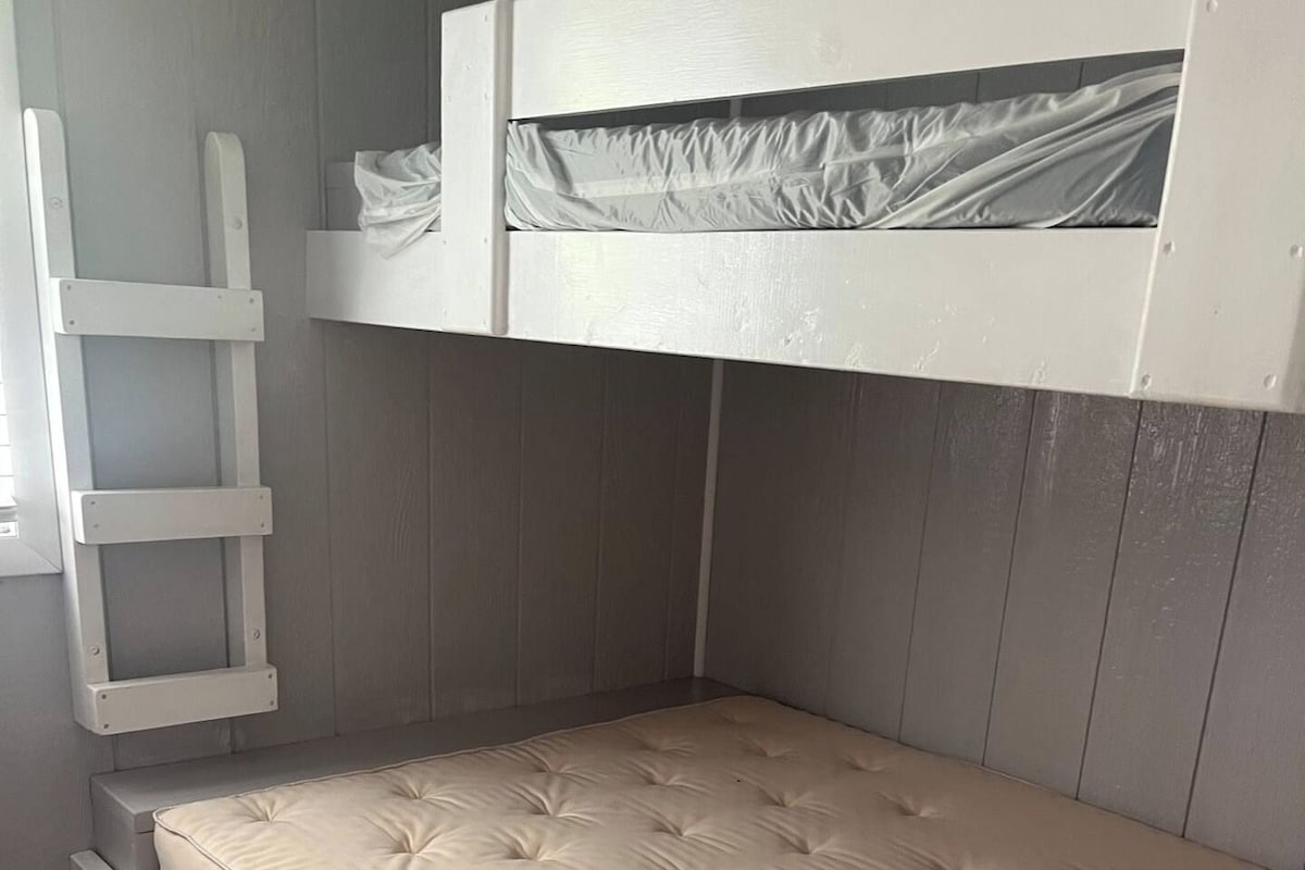 A bunk bed with a mattress and a ladder.
