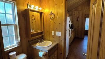 A wooden bathroom with a toilet, sink, and mirror.