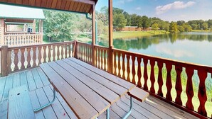 A wooden deck with a table and benches, overlooking a lake and greenery. - Splash Magic RV Resort (Northumberland)