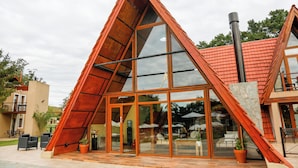 A modern building with a triangular roof, large glass windows, and a patio area with outdoor seating.