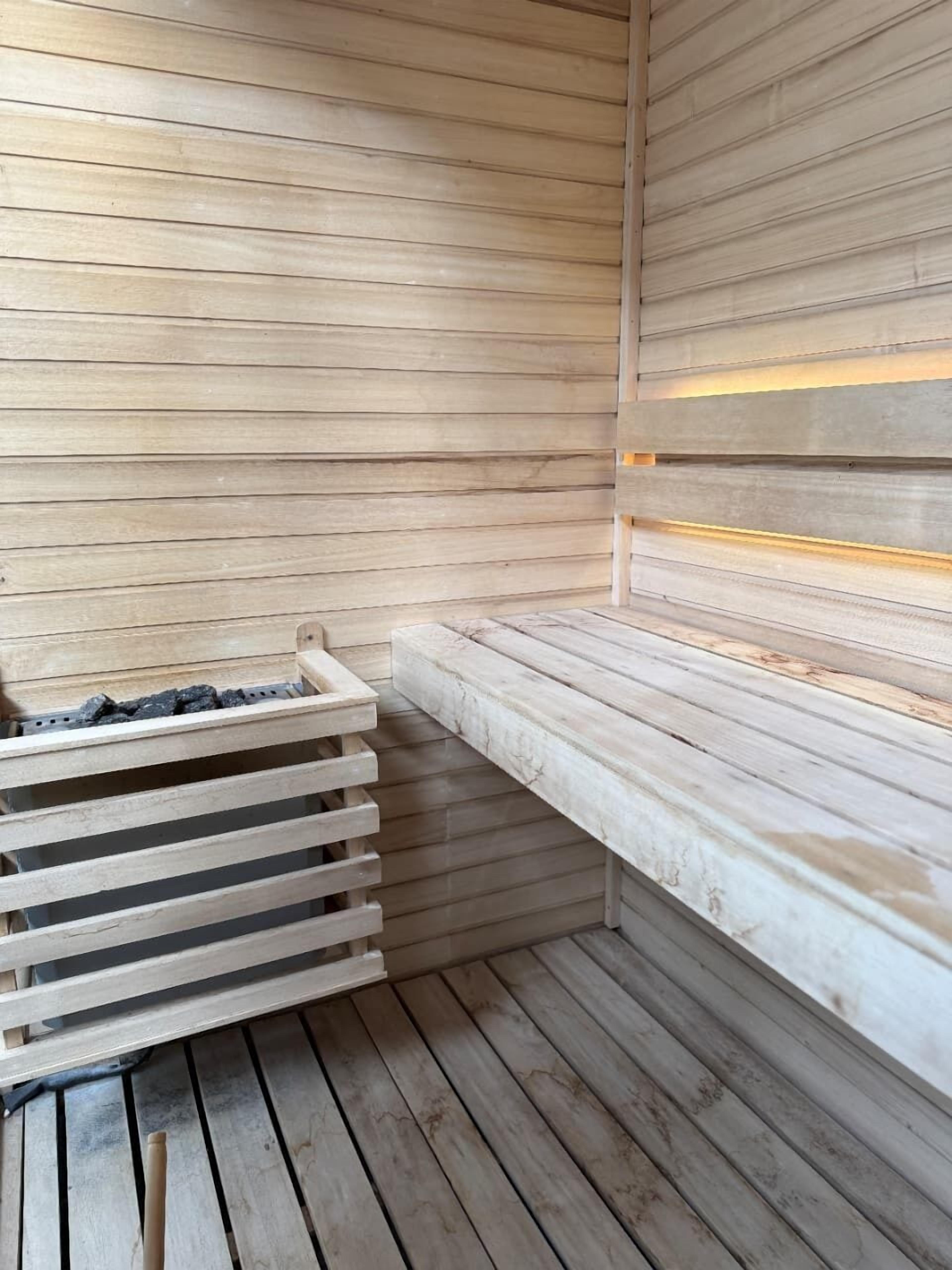 A sauna with wooden benches and a bench with a built-in heater.