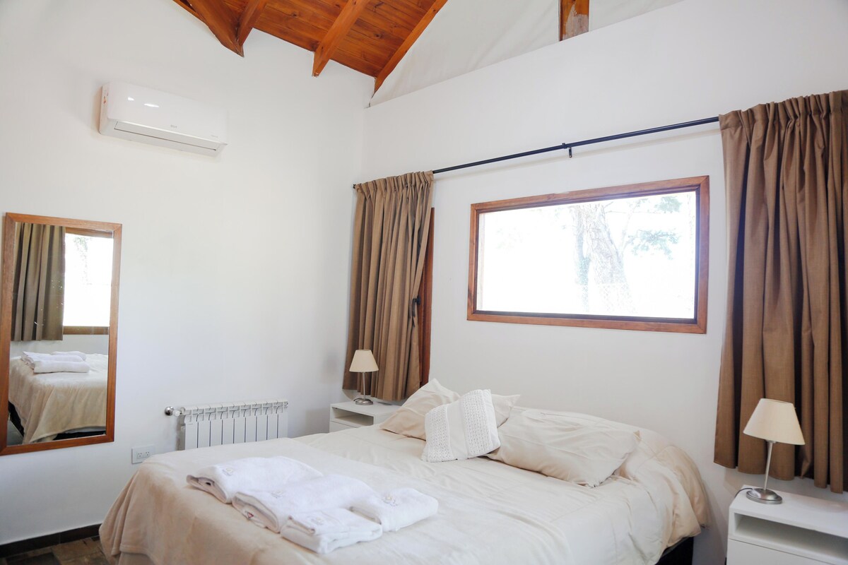 Un dormitorio con cama, mesita de noche, lámpara, ventana y radiador.