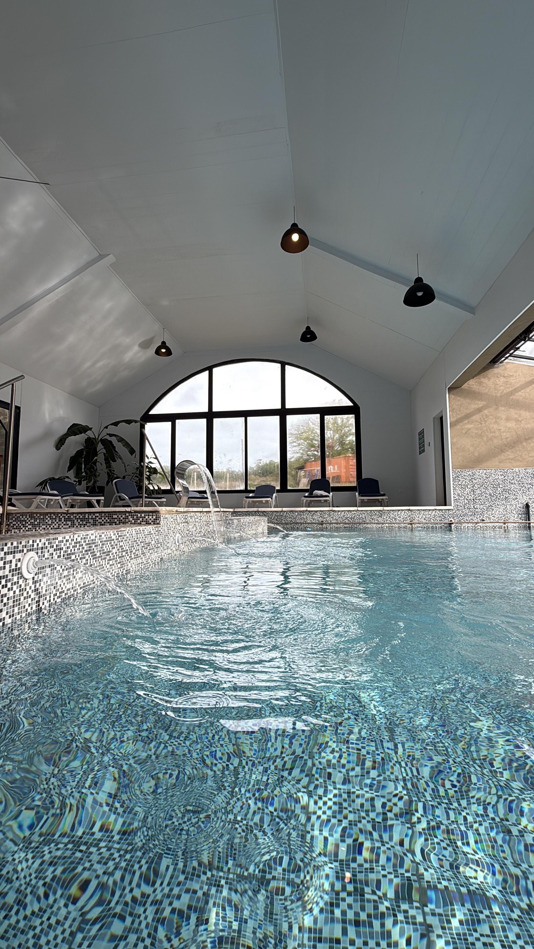 Una piscina techada, una piscina al aire libre, sombrillas