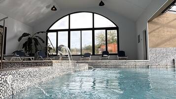 Una piscina techada, una piscina al aire libre, sombrillas