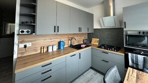 A modern kitchen with grey cabinets, a wooden countertop, a gas stove, and a microwave.