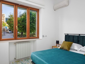 Ein Schlafzimmer mit einem Bett, einem Fenster, einer Heizung und einer Klimaanlage.