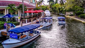 A canal with boats docked, a restaurant with outdoor seating, and a building with a red-tiled roof. - Luxury Fort Lauderdale Waterfront Home • Heated Pool • Game Room •  Park (Fort Lauderdale)