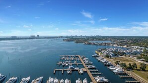 A marina with multiple docks and boats, surrounded by residential areas and a distant city skyline. - FREE Daily Golf! Reflections 406 Amazing Views, Heated Resort Pool & Hot Tub! (Panama City)
