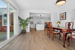 Ein geräumiger Essbereich mit Holztisch und -stühlen, einer Topfpflanze und Blick auf eine Ziegelaußenwand.