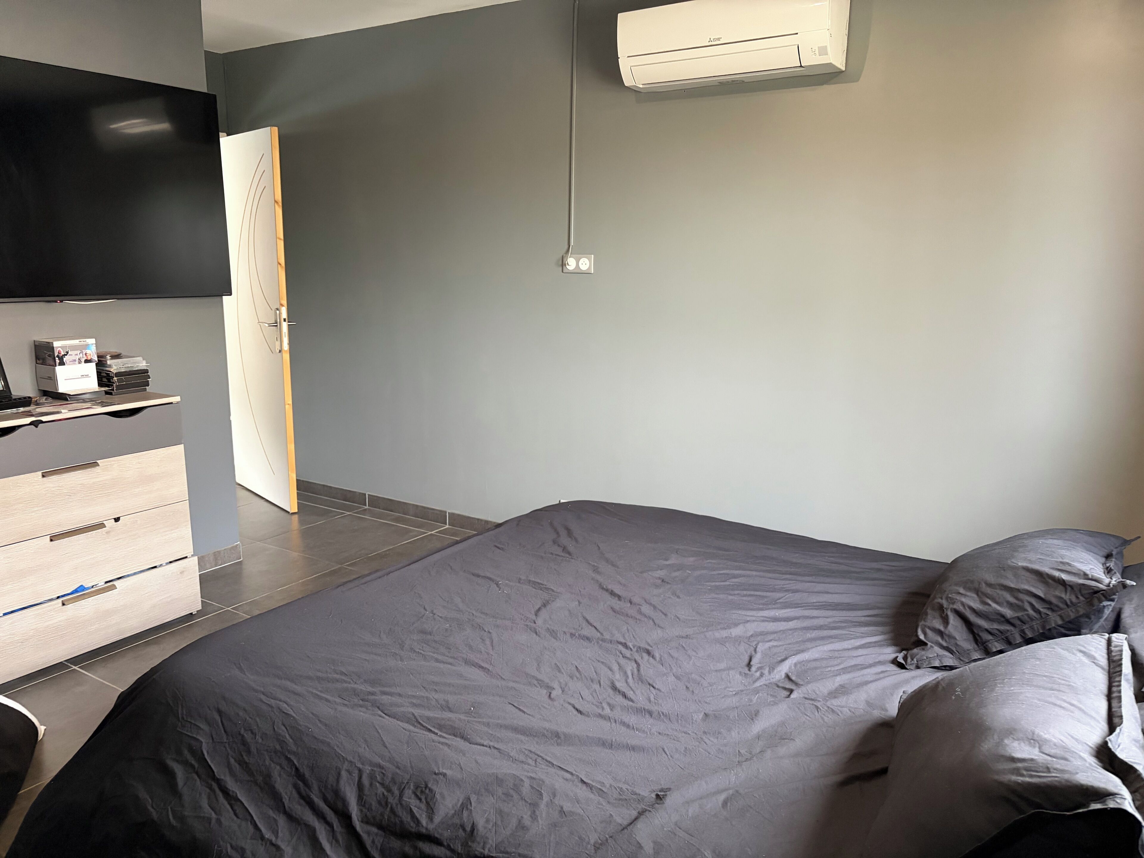 Un dormitorio con una cama, un escritorio, una silla y un aire acondicionado.