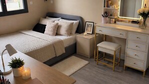 Ein Schlafzimmer mit Bett, Nachttisch, Schreibtisch, Stuhl und Kommode mit Spiegel.