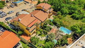 A multi-story residential building with a swimming pool, surrounded by greenery and parked cars. - Pool and Garden Apartment Hortenzija (Kostrena)