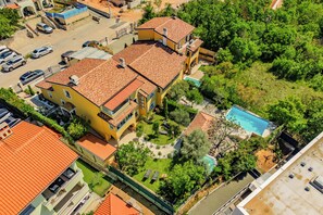A multi-story residential building with a swimming pool, surrounded by greenery and parked cars. - Pool and Garden Apartment Hortenzija (Kostrena)